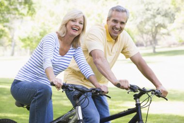 Couple on bikes outdoors smiling clipart