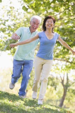 Couple running outdoors in park by lake smiling clipart