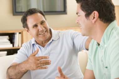 Two men in living room talking and smiling clipart
