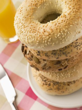 Stack of Seeded Bagels with a Glass of Orange Juice clipart