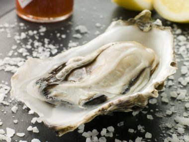 Opened Rock Oyster with Hot Chilli Sauce Lemon and Sea Salt clipart
