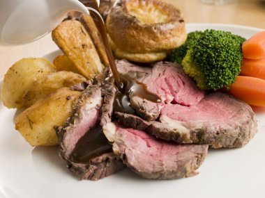 Gravy being Poured on a plate of Roast Beef and Yorkshire Puddin clipart