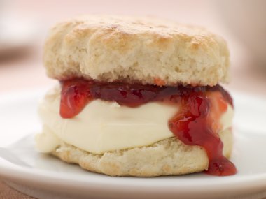 Scone Filled with Strawberry Jam and Clotted Cream on a plate clipart
