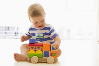 Baby indoors playing with truck clipart