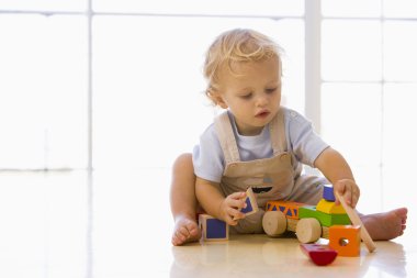 Baby indoors playing with toy truck clipart