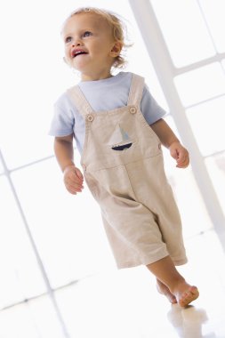 Young boy walking indoors smiling clipart