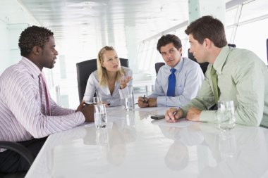 Four businesspeople in a boardroom talking clipart