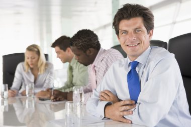 Four businesspeople in a boardroom smiling clipart