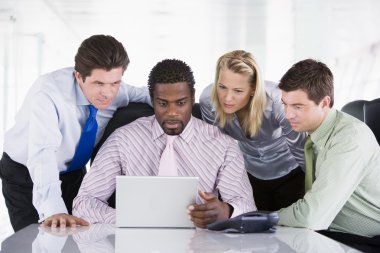 Four businesspeople in a boardroom looking at laptop clipart