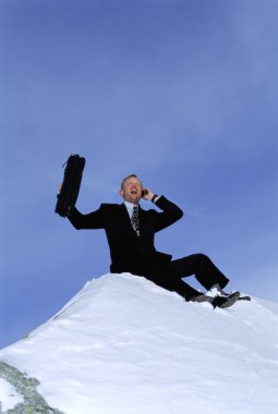 Businessman outdoors on snowy mountain using cellular phone and clipart