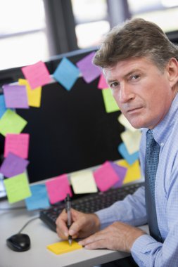 Businessman in office at monitor with notes on it writing clipart