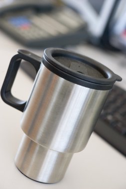 Shot of a reusable coffee cup on a desk clipart