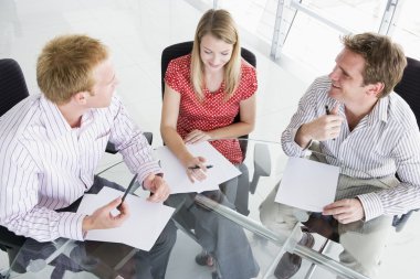 Three businesspeople in a boardroom looking at paperwork clipart