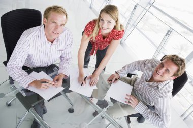 Three businesspeople in a boardroom with paperwork smiling clipart