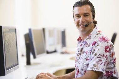 Man wearing headset in computer room smiling clipart