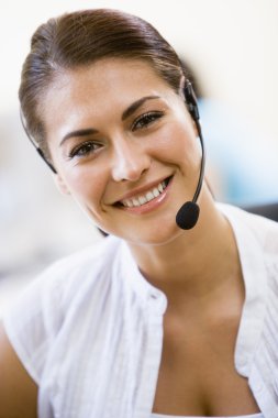 Woman wearing headset indoors smiling clipart