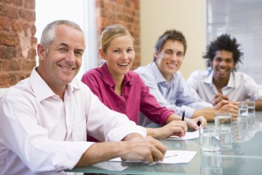 Four businesspeople in boardroom smiling clipart