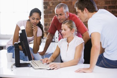 Four businesspeople in office space looking at computer smiling clipart