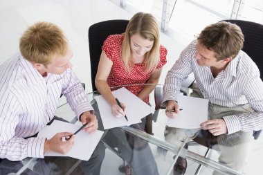 Three businesspeople in boardroom with paperwork clipart