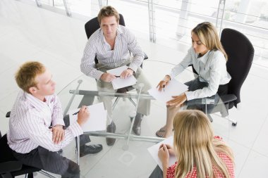 Four businesspeople in boardroom with paperwork clipart