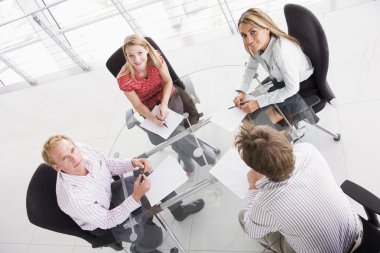 Four businesspeople in boardroom with paperwork smiling clipart