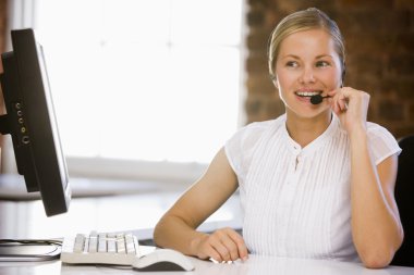 Businesswoman wearing headset in office smiling clipart