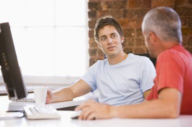 Two businessmen in office drinking coffee and talking clipart