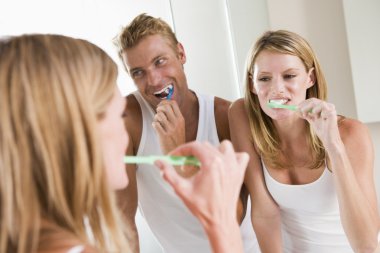 Couple in bathroom brushing teeth clipart