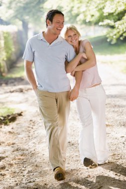 Couple walking outdoors arm in arm smiling clipart