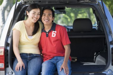 Couple sitting in back of van smiling clipart