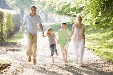 Family running outdoors holding hands and smiling clipart