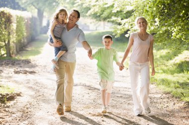 Family walking outdoors holding hands and smiling clipart