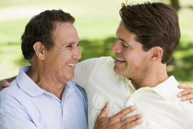 Two men standing outdoors bonding and smiling clipart