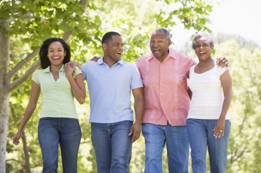 Two couples walking outdoors arm in arm smiling clipart