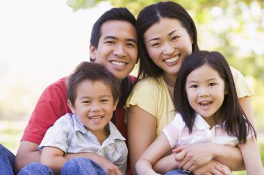 Family sitting outdoors smiling clipart