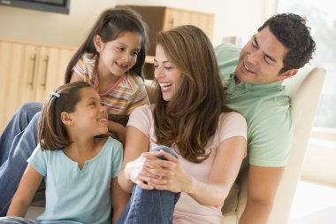 Family sitting in living room smiling clipart