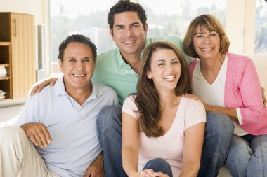 Two couples sitting in living room smiling clipart