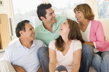 Two couples sitting in living room smiling and laughing clipart