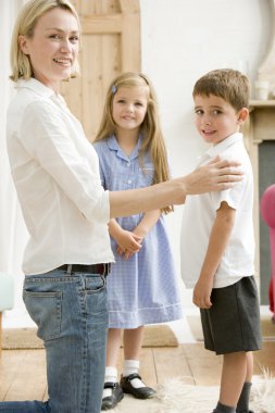 Woman in front hallway with two young children smiling clipart