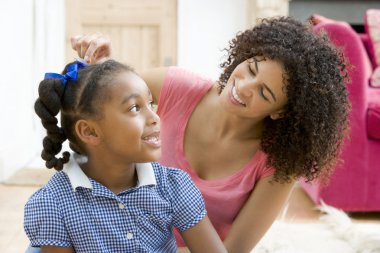 Woman in front hallway fixing young girl's hair and smiling clipart