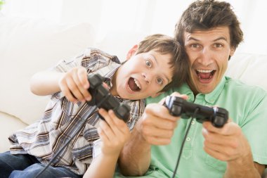 Man and young boy with video game controllers smiling clipart