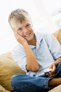 Young boy in living room with MP3 player smiling clipart