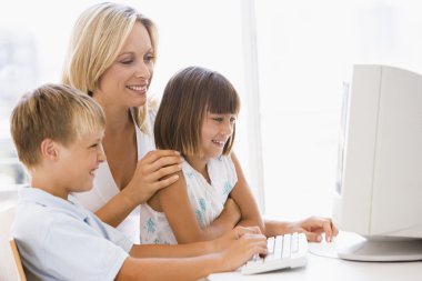 Woman and two young children in home office with computer smilin clipart