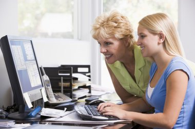 Woman and girl in home office with computer smiling clipart