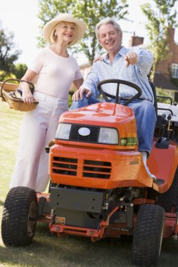 Couple outdoors with tools and lawnmower pointing and smiling clipart