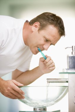 Man in bathroom brushing teeth clipart