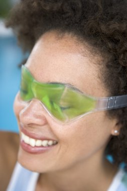 Woman sitting poolside using eye mask smiling clipart