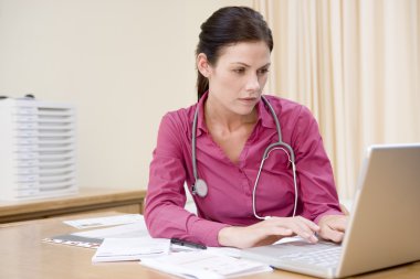 Doctor using laptop in doctor's office clipart