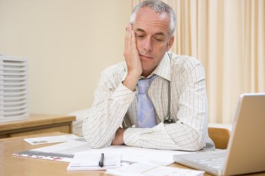 Doctor with laptop in doctor's office clipart