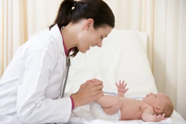 Doctor giving checkup to baby in exam room smiling clipart